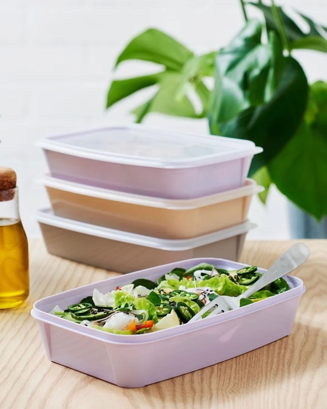 In the foreground, an open SmartStore Easy 1.2-litre food storage container with a portion of salad inside. In the background, more of the same containers stacked together.