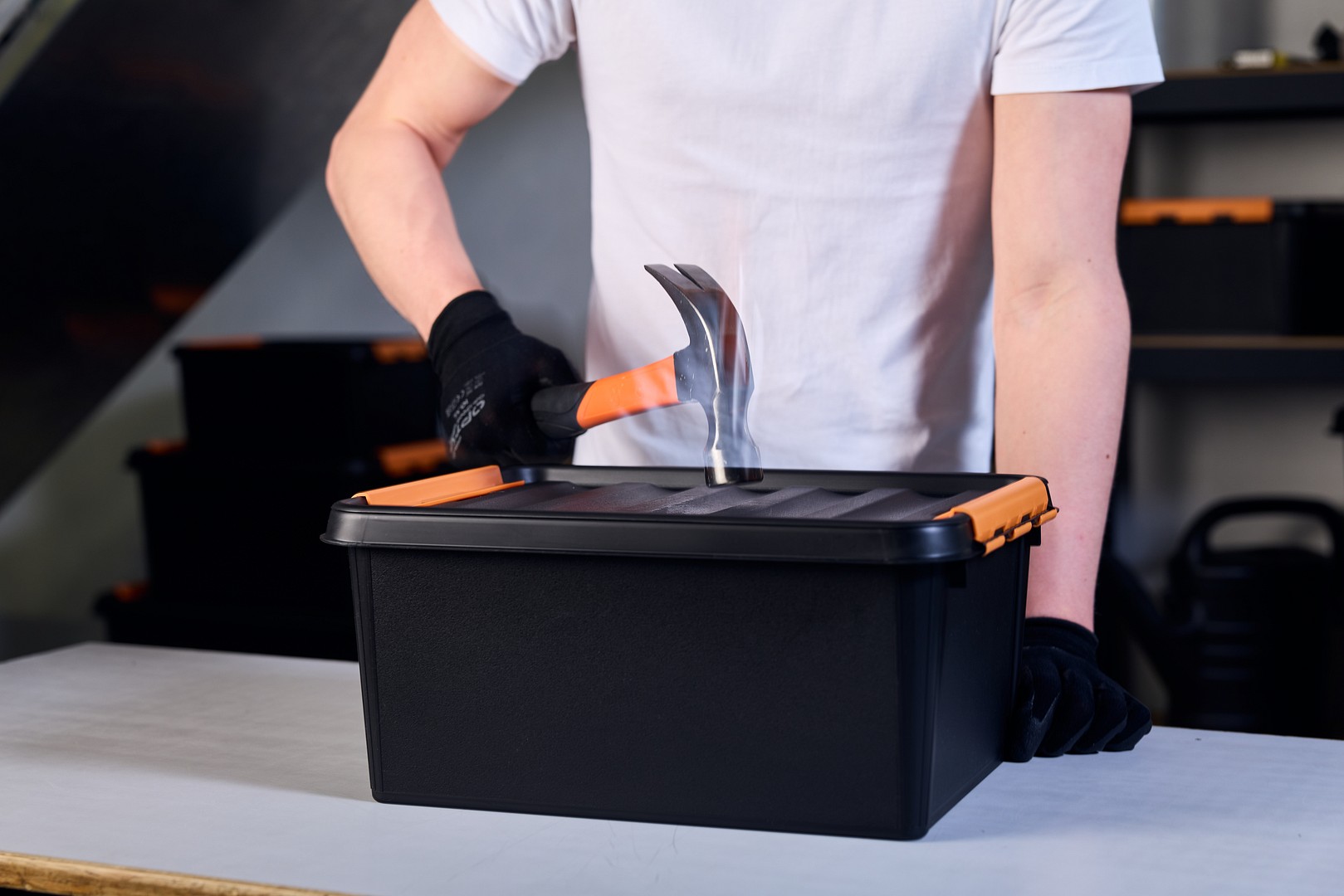 Eine Hand mit einem Hammer, der auf eine SmartStore Pro Box schlägt