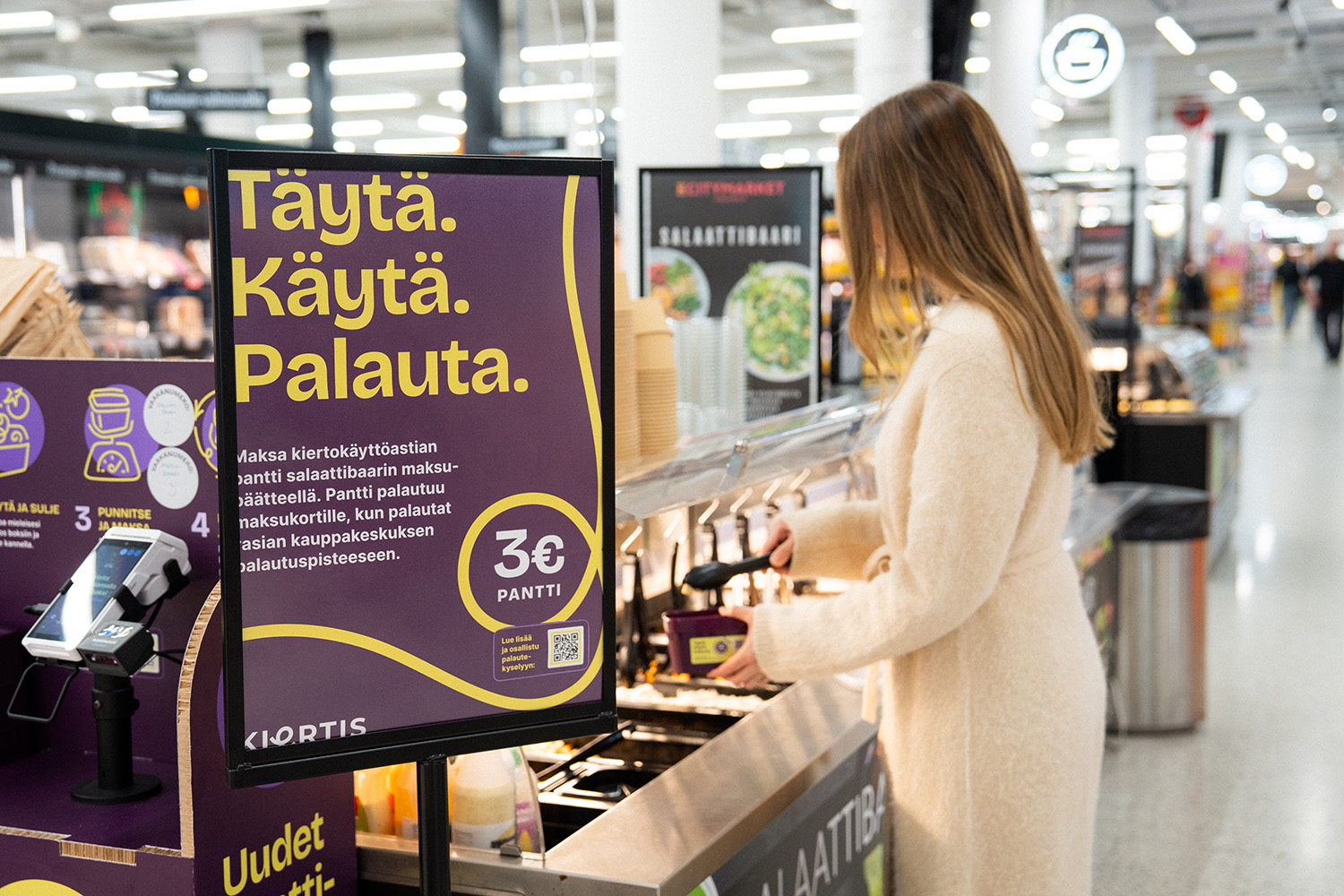 A woman in a salad bar holding a reusable food container